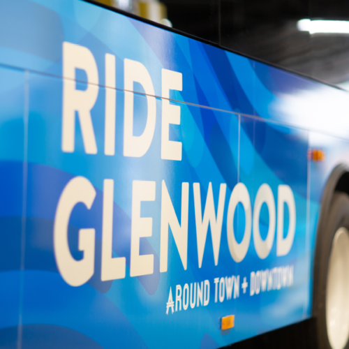 Close up picture of the bus with white tagline of Ride Glenwood tagline on blue background