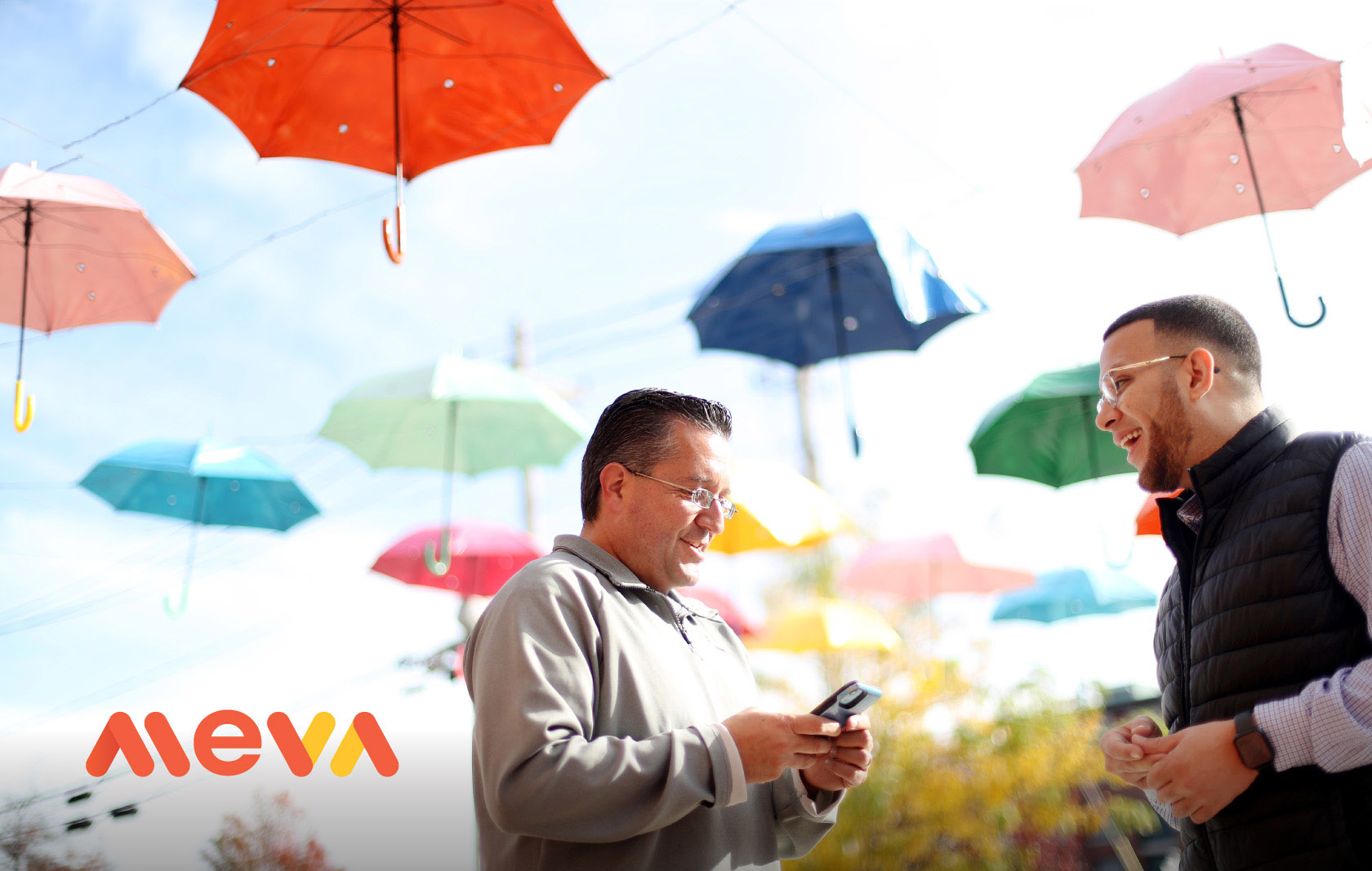 Two men talking in the foreground, colorful umbrellas filed background