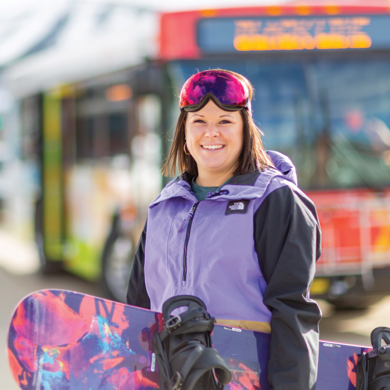 Snowboarder standing with bus in the background